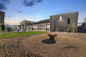 A modern outdoor patio with a fire pit, seating, and a view of the house. - 37 Sand Piper - Echuca Holiday Homes (Moama)