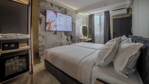 A hotel room with a bed, a TV mounted on the wall, a minibar, and a wall-mounted air conditioning unit. - Aslan Gold Hotel (Varna)