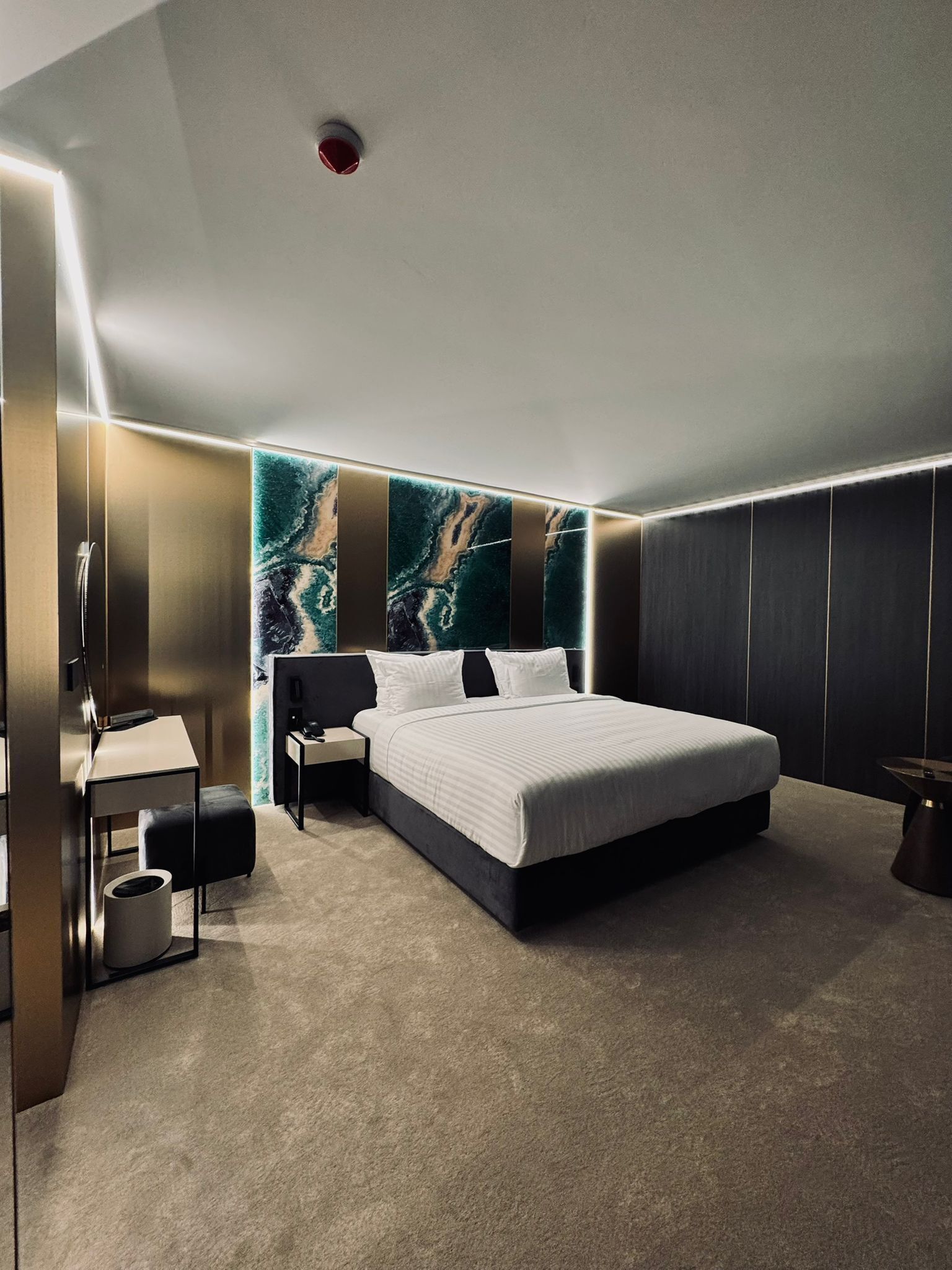 Une chambre à coucher moderne avec un grand lit, un bureau et une table de chevet.