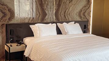 Un dormitorio moderno con una cama grande, una mesita de noche y una pared con diseño de mármol.
