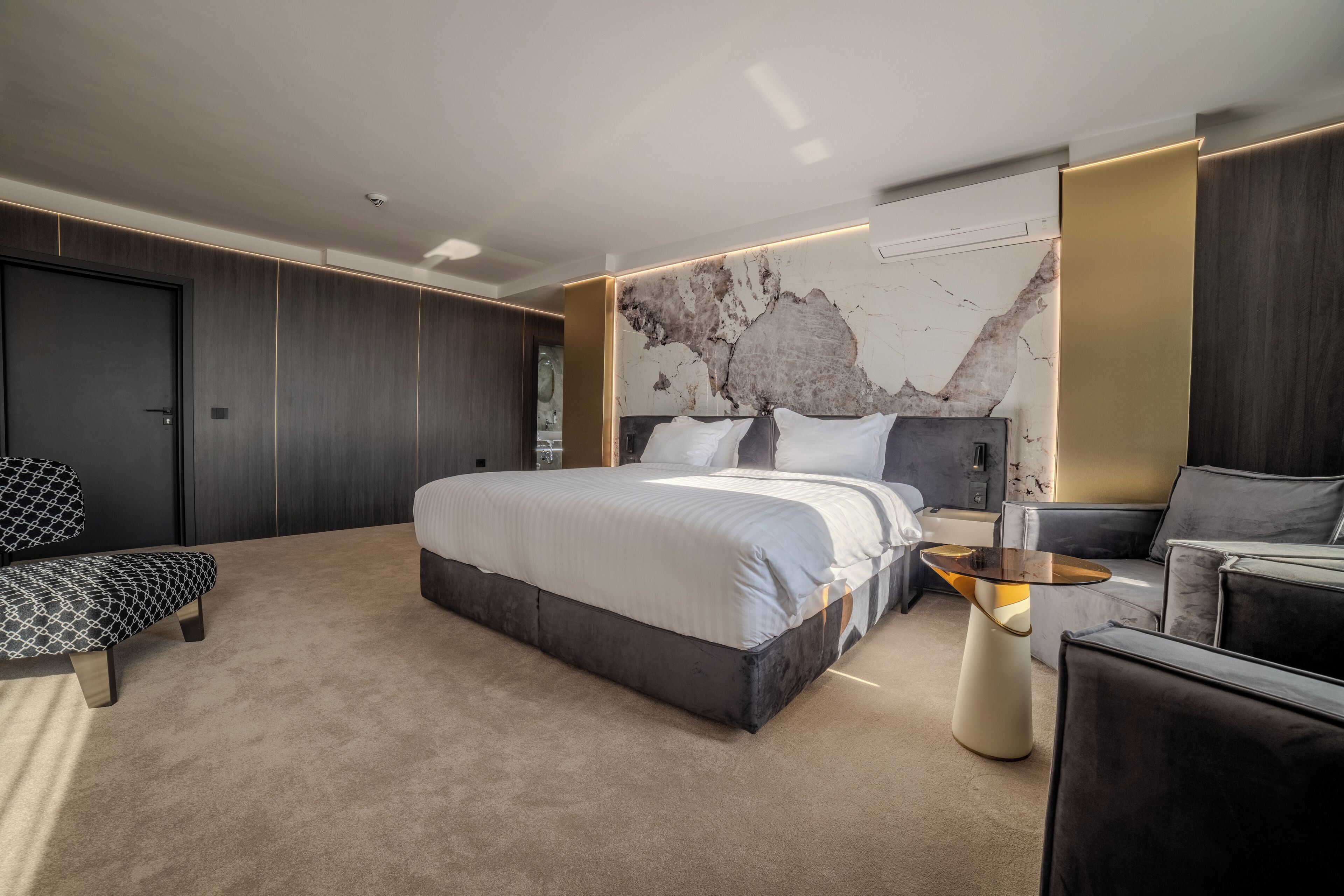 A modern bedroom with a large bed, a sofa, a coffee table, and a wardrobe.