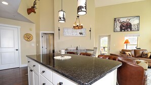 Un'ampia cucina con una grande isola, mobili bianchi e un'area pranzo con una comoda divano in pelle marrone.
