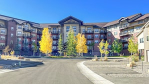 Un edificio residenziale a più piani con balconi, un cortile interno e alberi dai colori autunnali.