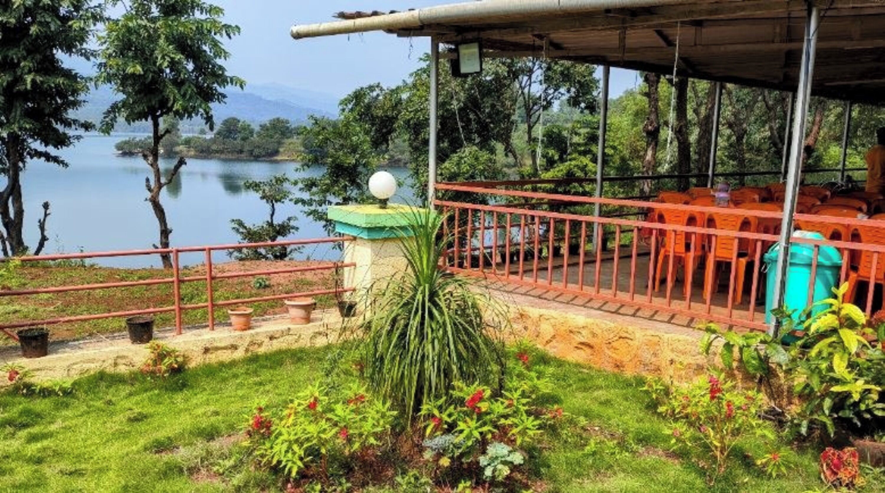 A covered outdoor seating area with a view of a lake and trees.