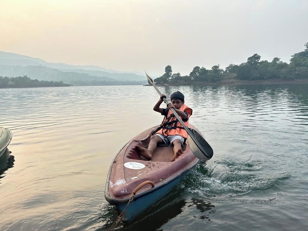 Eine Person in einem kleinen Boot auf ruhigem Wasser, mit einer fernen Küstenlinie und Hügeln im Hintergrund.
