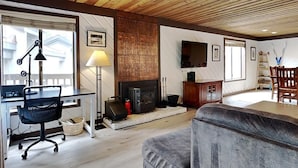 A living room with a fireplace, a sofa, a TV, and a wooden ceiling. - Slopeside Condo with Fireplace (Mammoth Lakes)