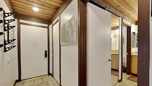 A hallway with wooden flooring, a patterned rug, and a door with a map on the wall. - Slopeside Condo with Fireplace (Mammoth Lakes)