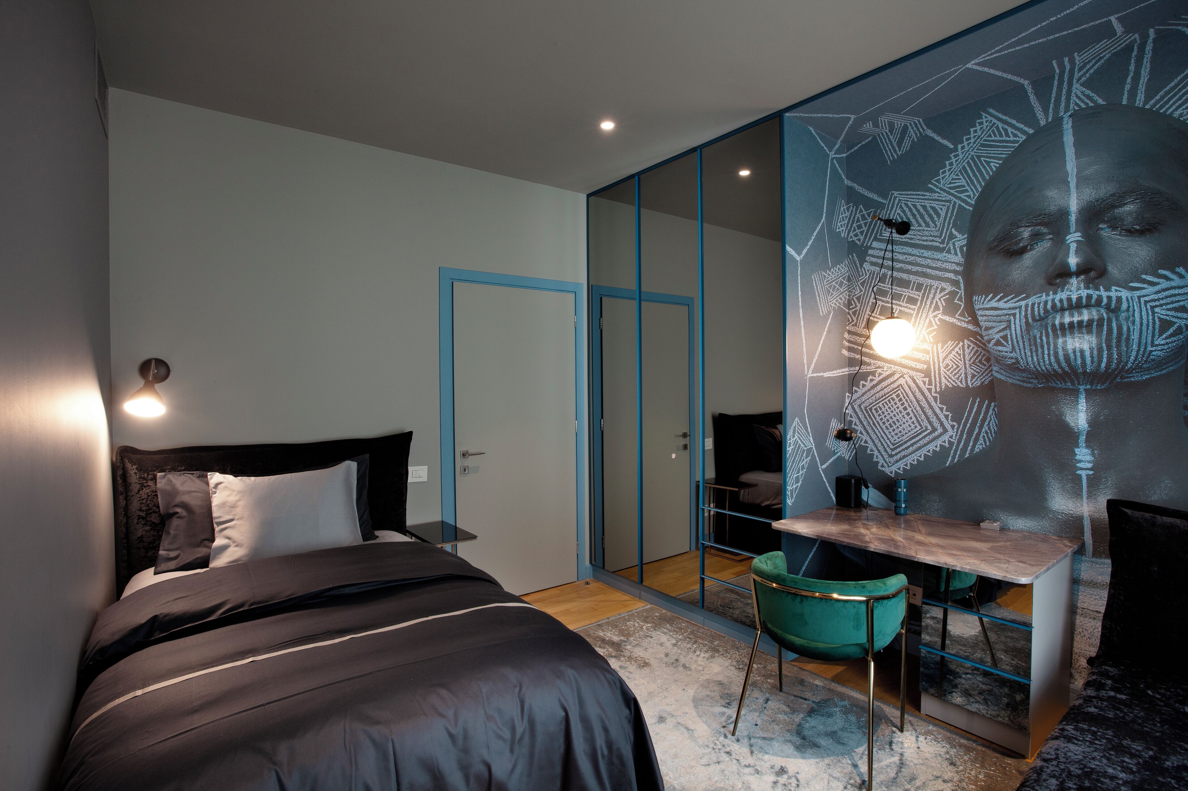 Une chambre moderne avec un lit, un bureau et une chaise. Un grand miroir est accroché au mur.