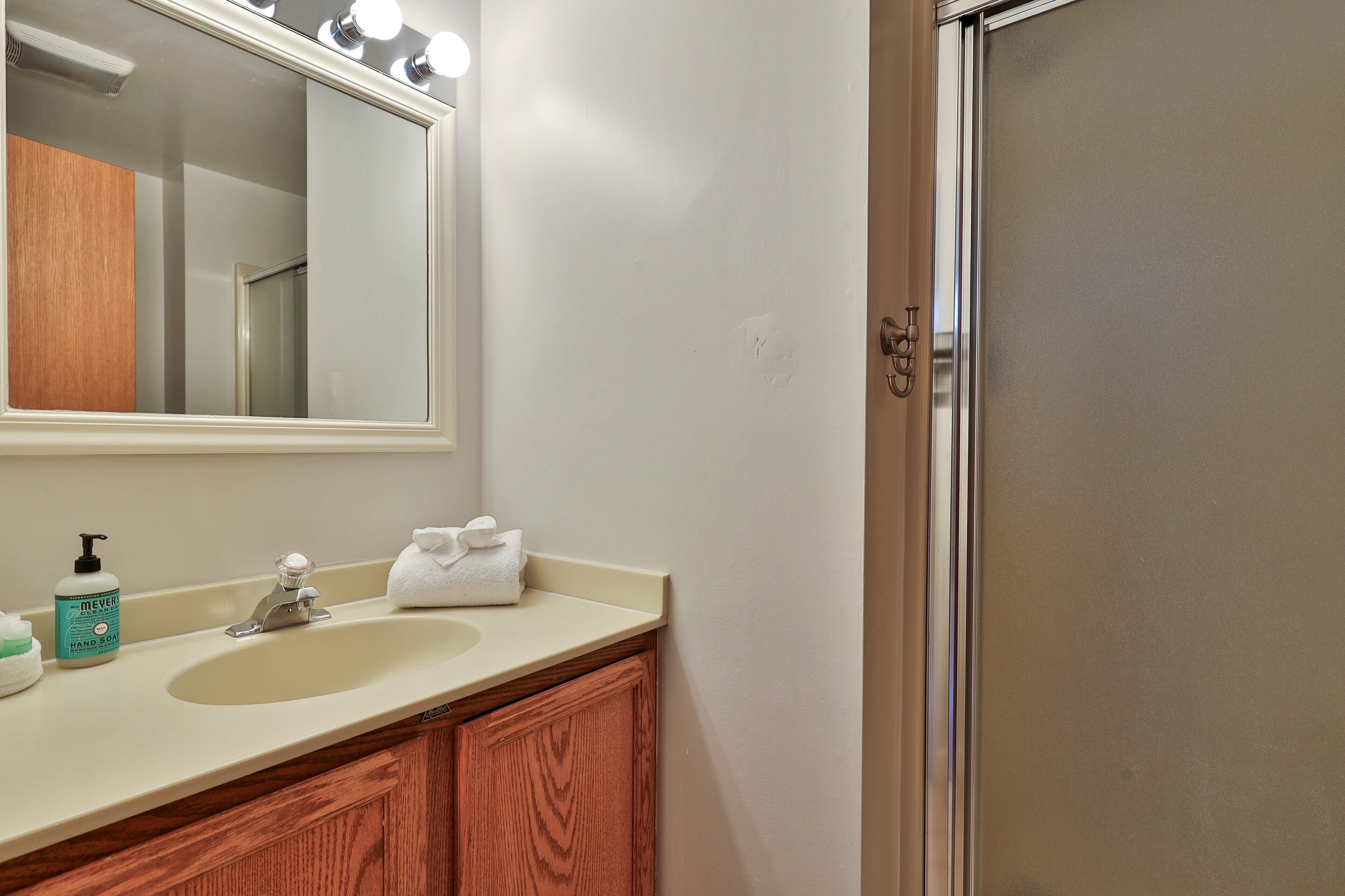 A bathroom with a sink, mirror, and wooden vanity.