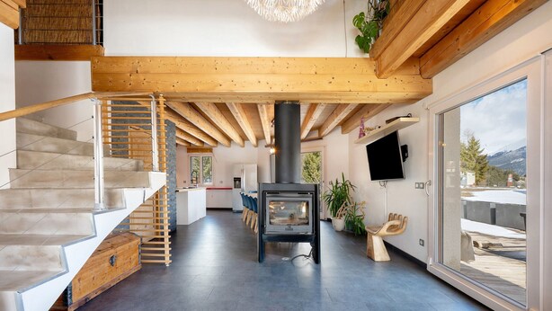 Een modern interieur met een trap, een open haard en een groot raam met uitzicht.