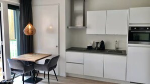 Ett modernt kök med vita skåp, en ugn i rostfritt stål och en svart bänkskiva.