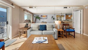 Una sala de estar con sofá, mesa de centro y un comedor con una silla y una lámpara.