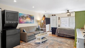 A compact living space with a kitchenette, a sofa, a coffee table, a bed, and a painting on the wall. - Old Town Studio Cottage with Full Kitchen, In-Unit Laundry & Shared Pool (Key West)