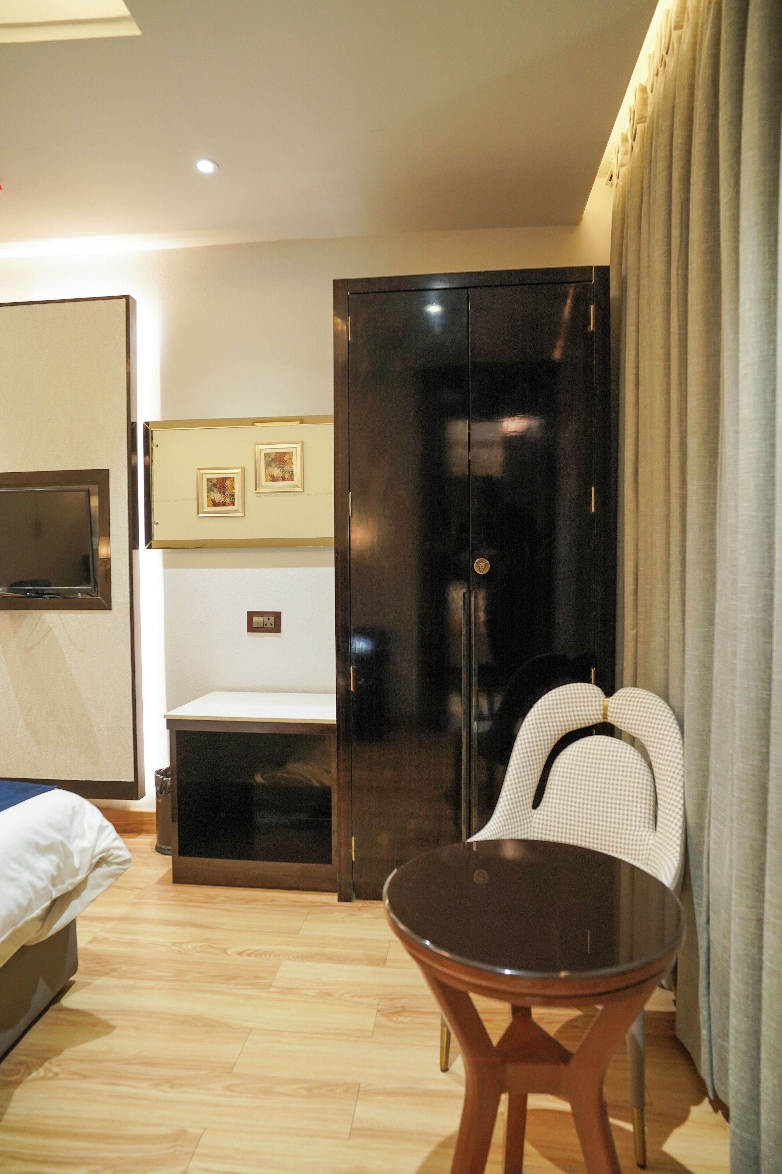 A hotel room with a bed, a desk, a chair, a wardrobe, and a television.