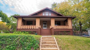 A two-story brick house with a front porch, a set of stairs leading to the entrance, and a well-maintained lawn. - Warm, Cozy and Historic (Poplar Bluff)