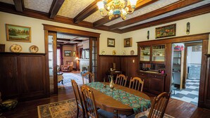 A dining room with a wooden table, chairs, and a chandelier. There is a kitchen area visible through an open doorway. - Warm, Cozy and Historic (Poplar Bluff)