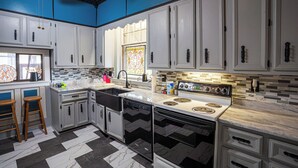 A modern kitchen with white cabinets, a black and white tiled floor, and a large stove. - Warm, Cozy and Historic (Poplar Bluff)
