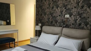 Quarto de hotel com uma cama grande, uma escrivaninha e um espelho.