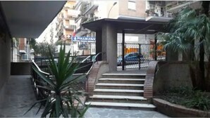 Entrada de um edifício com escadaria que leva a uma área cercada.