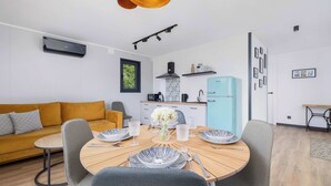 A modern living space with a dining area, sofa, kitchen, and a light blue refrigerator. - Modern House | Garden | Air Conditioning | Close to the Forest (Bielsko-Biała)
