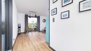 A modern interior with a wooden floor, a dining area with a table and chairs, and framed pictures on the wall. - Modern House | Garden | Air Conditioning | Close to the Forest (Bielsko-Biała)