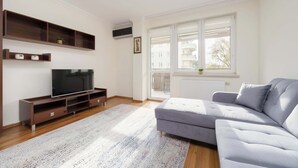 Ein modernes Wohnzimmer mit einem grauen Sofa, einem Flachbildfernseher auf einem Holzboden und eingebauten Regalen.
