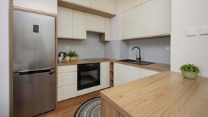 Eine moderne Küche mit Edelstahlkühlschrank, integriertem Backofen und einer Holzarbeitsplatte.