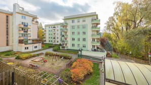 Ein Wohngebäude mit mehreren Balkonen, einem Spielplatz und umgebender Bepflanzung.