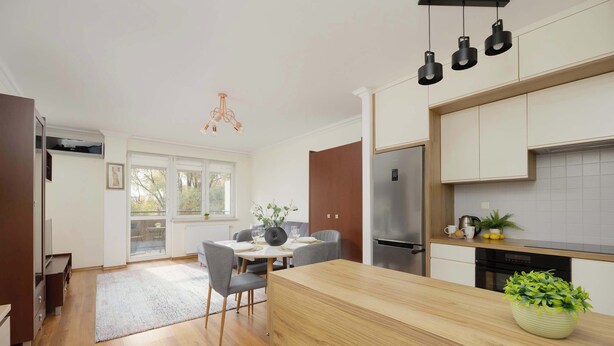 Eine moderne Küche mit Holzarbeitsplatte, integriertem Backofen und einem Edelstahlkühlschrank. Ein Essbereich mit Tisch und Stühlen sowie ein großes Fenster, das für natürliches Licht sorgt.
