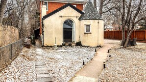A house with a small attached garage, a pathway leading to the garage, and a wooden fence in the background.