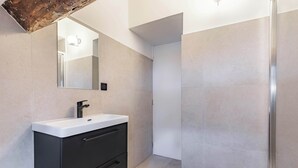 A modern bathroom with a white sink, black cabinet, and a mirror. - 11 Beaumarchais 5D (Paris)