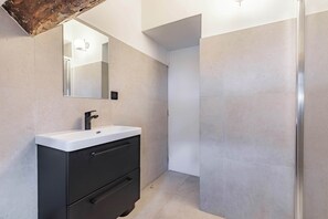 Ein modernes Badezimmer mit einem weißen Waschbecken, einem schwarzen Schrank und einem Spiegel.