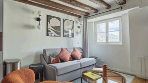 A modern living room with a grey sofa, orange armchair, and a glass coffee table.