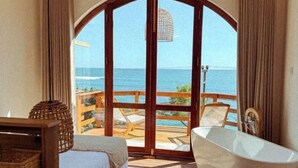 A room with a large arched doorway, a bathtub, a bed, and a view of the ocean. - Ocean Bliss by Sugar Coliving (Matara)
