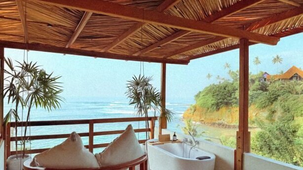 A room with a bathtub, wooden seating, and a view of the ocean. - Ocean Bliss by Sugar Coliving (Matara)