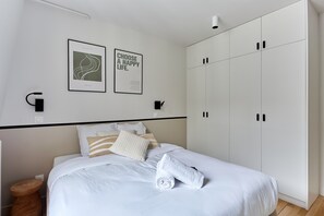 Ein Schlafzimmer mit einem Bett, zwei Wandleuchten, einem Kleiderschrank und zwei gerahmten Postern.