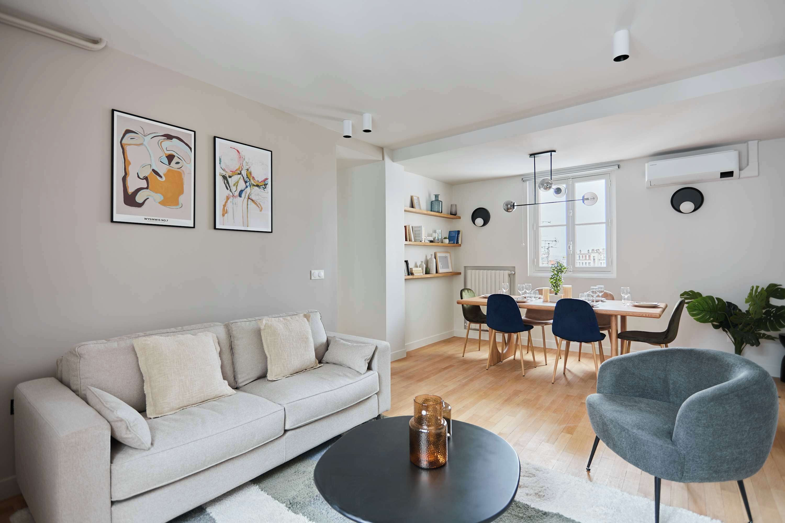 A modern living room with a sofa, a coffee table, and a dining area with chairs and a table.