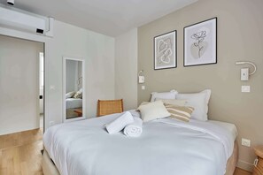 A bedroom with a bed, a mirror, and two framed artworks on the wall. - Large apartment Arc de Triomphe (Paris)