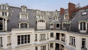 A multi-story building with a classic architectural style, featuring arched windows and balconies. - Large apartment Arc de Triomphe (Paris)