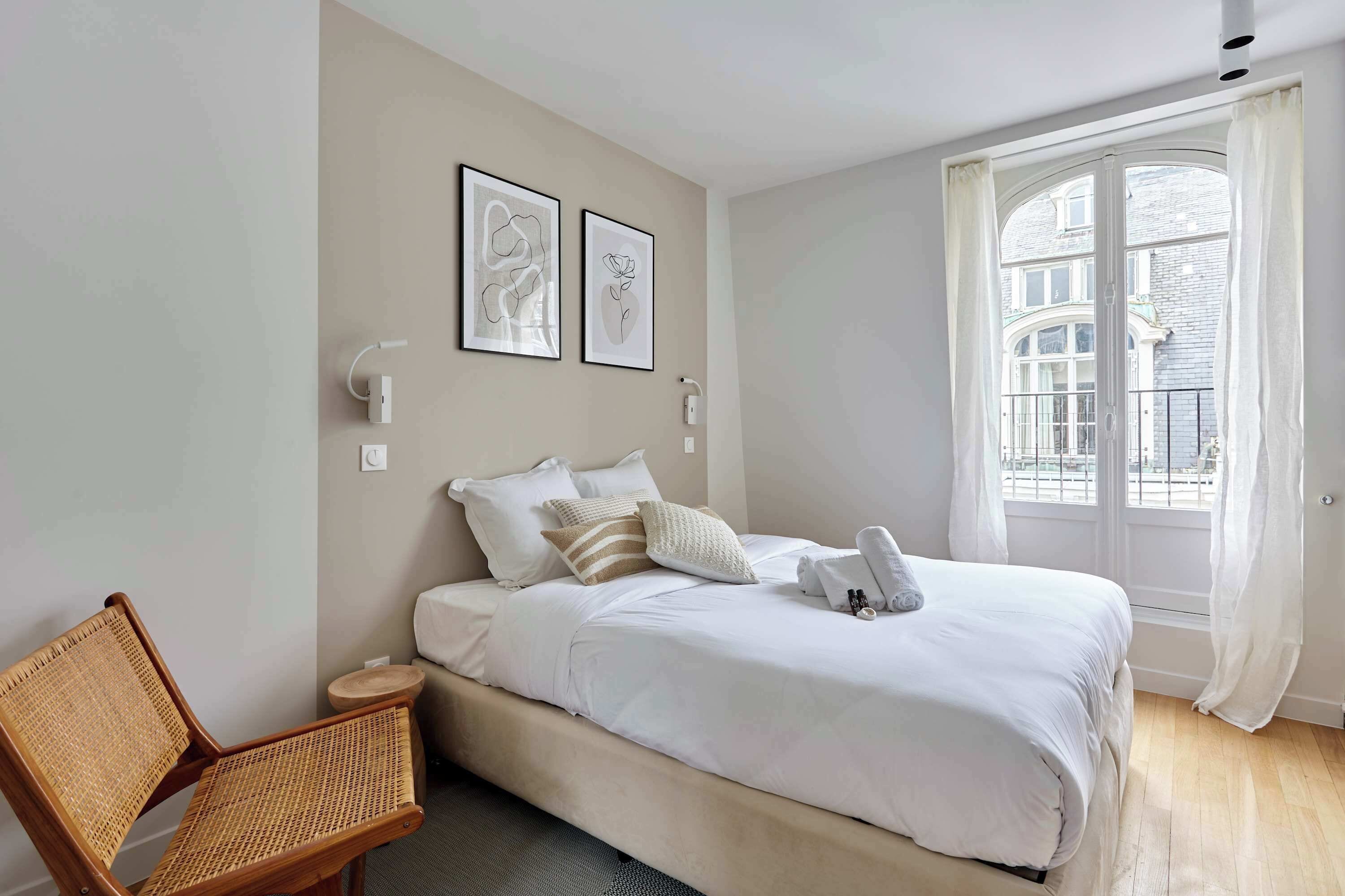 A bedroom with a bed, a chair, and two wall-mounted light switches.