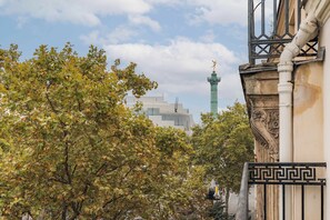Un edificio con una reja decorativa y un árbol con hojas otoñales al frente.