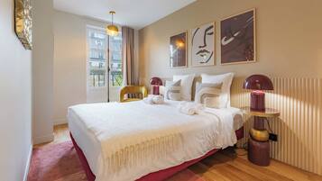 Een hotelkamer met een groot bed, een stoel, een tafel en kunst aan de muur.