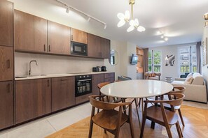 Una cocina moderna con armarios de madera, microondas integrado y horno. En el centro, hay una mesa de comedor con sillas.