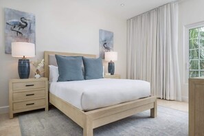 Ein Schlafzimmer mit einem Bett, zwei Nachttischen, einem Fenster mit Vorhängen und Kunstwerken an den Wänden.