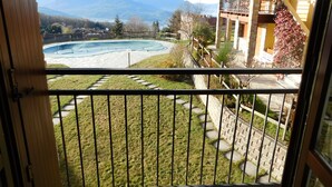 A balcony with a view of a swimming pool, a stone pathway, and a mountainous landscape. - Rosemary 2 apartment in Agra with pool (Agra)