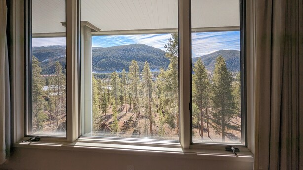 Una habitación con un ventanal que ofrece vistas a un paisaje montañoso boscoso.