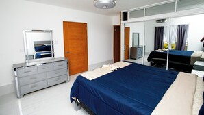 Un dormitorio moderno con una cama grande, un aparador, un espejo y un armario.