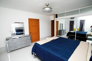 A modern bedroom with a large bed, a dresser, a mirror, and a wardrobe. - Apartment with pool and view, minutes away from Cofresí and Costambar beaches. (Cofresi)