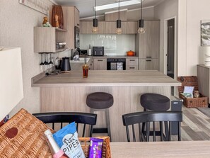 Una cuina moderna amb una illa central, tamborets de bar i una taula de menjador.