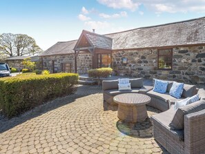 A stone building with a reception area, outdoor seating, and a paved patio. - 38 at the Sanctuary Lodges - UK50850 (Rhosfawr, near Pwllheli)